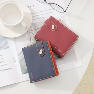 Detailed view of burgundy and navy wallets with golden leaf buckles and inner contrast