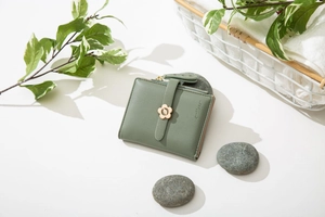 Nahaufnahme der grünen kurzen Bifold-Geldbörse mit goldener Blume und Blattprägung