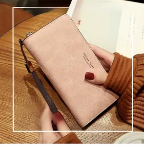 Detail of pink long wallet with litchi texture, hand strap, and Forever Young logo