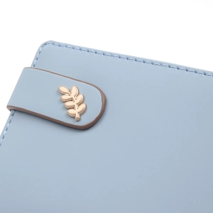 Close-up of light blue leather wallet featuring a golden leaf buckle and fine stitching