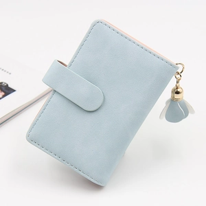 Detail view of light blue short wallet with matte texture and floral pendant charm