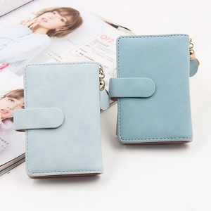 Close-up of light blue matte leather wallets with metal chain and leather tassel charms