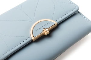 Detail of light blue quilted wallet with golden flower buckle and brand engraving