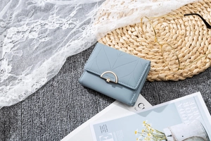 Detail of light blue tri-fold wallet with leaf quilting and gold flower buckle
