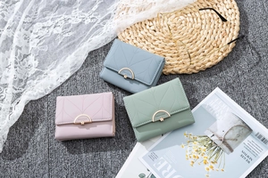 Close-up of leaf-patterned wallets in blue, pink and green with gold metal buckles