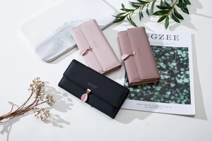 Detailed view of long leather wallets in pink and black with leaf charms and matte texture