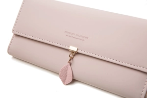 Detail of pink faux leather wallet with white stitching and leaf pendant ornament