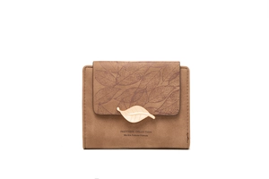 Close-up of brown suede trifold wallet with decorative gold leaf buckle and engraved text