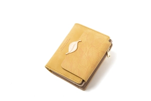 Detail of leaf-shaped metal buckle and heart-shaped zipper on mustard yellow leather wallet