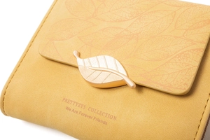 Detail of yellow trifold wallet with gold leaf buckle and embossed leaf pattern
