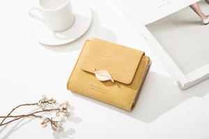 Detailed view of yellow faux leather wallet with leaf texture and gold metal buckle
