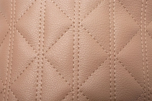 Gros plan d'un sac en cuir matelassé rose montrant le grain de litchi et les coutures