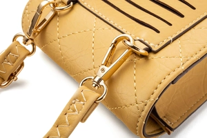 Detail der gelben gesteppten Handytasche mit goldenem Metallverschluss und Naht