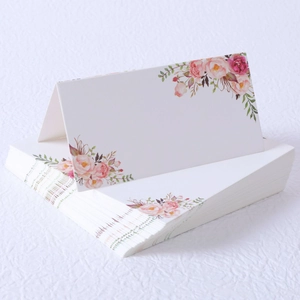 Close-up of foldable white place cards with elegant watercolor pink and orange flowers