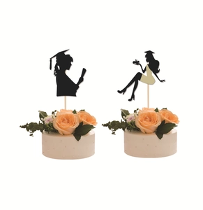 Macro detail of black graduation cake toppers with female silhouettes and academic caps