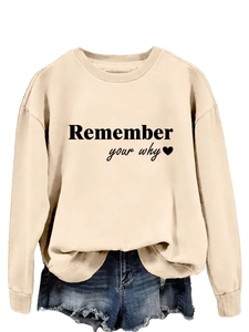 Dettaglio della scritta Remember Your Why su una felpa girocollo beige chiaro in cotone