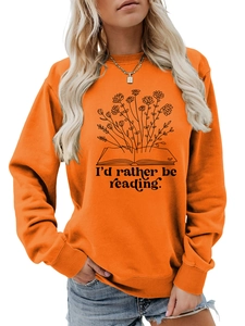Detail of orange sweatshirt featuring a floral book illustration and reading quote