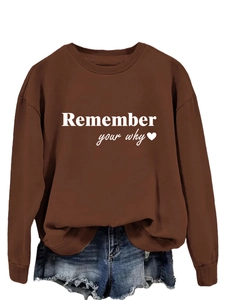Dettaglio della stampa Remember Your Why con cuore su felpa oversize marrone scuro