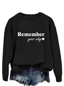 Dettaglio dello slogan bianco 'Remember your why' e cuore su una felpa nera girocollo