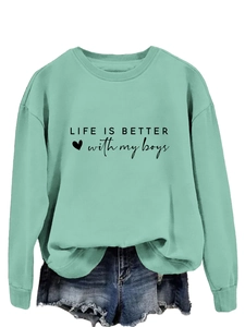 Détail d'un sweat vert menthe avec imprimé Life is better with my boys et icône de cœur