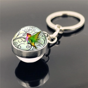 Hummingbird crystal glass ball keychain with silver metal ring on reflective surface