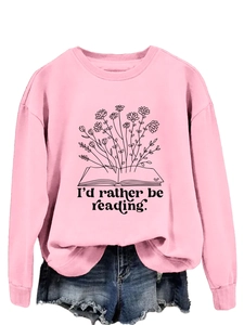 Detail of pink sweatshirt featuring flower bouquet growing from a book with reading quote