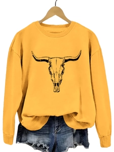 Détail d'un sweat à col rond jaune gingembre avec imprimé tête de taureau et short en jean