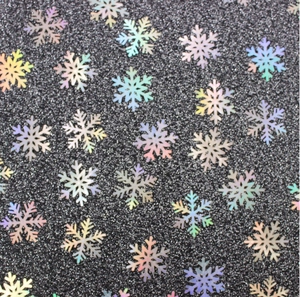 Close-up of holographic snowflake sequins with iridescent glitter on dark background