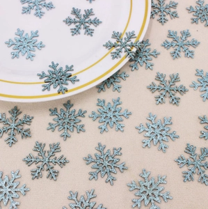 Close-up of sparkling light blue glitter snowflake confetti on a white ceramic plate