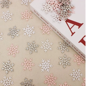 Detailed view of white, pink, and silver glitter snowflake confetti on a textured fabric
