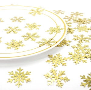 Close-up of sparkling gold snowflake confetti on a white plate for Christmas party decor