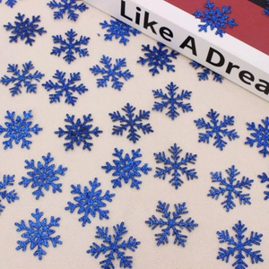Macro shot of dark blue glitter snowflake confetti on a rustic linen background