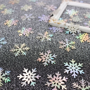 Iridescent snowflake confetti sequins for Christmas party decoration on black background