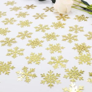 Golden snowflake confetti and sequins for Christmas party decorations on white surface