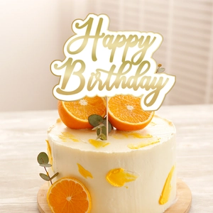 Golden Happy Birthday cake topper on cream cake with orange slices and leaves