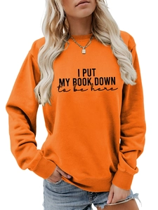 Close-up of orange crewneck sweatshirt with I Put My Book Down black letter print