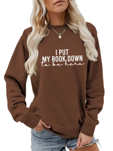 Detail of white text print on a caramel brown crewneck sweatshirt with ribbed collar