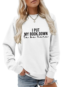 Close-up of white crewneck sweatshirt featuring 'I PUT MY BOOK DOWN' graphic print text