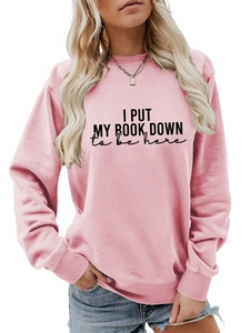 Detailed close-up of pink crewneck sweatshirt with slogan I put my book down to be here