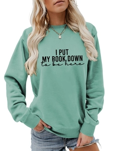 Detail of mint green sweatshirt featuring ribbed cuffs and bold printed slogan text