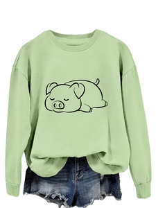 Close-up of a light green sweatshirt featuring a cute cartoon pig line art illustration
