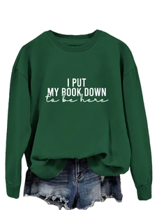 Detailed view of the dark green cotton sweatshirt featuring white printed quote lettering