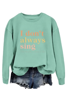 Close-up of mint green long sleeve sweatshirt featuring a colorful graphic text print