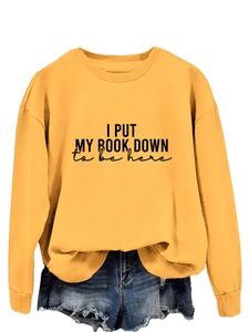 Detail of yellow sweatshirt featuring I PUT MY BOOK DOWN print and drop shoulder design