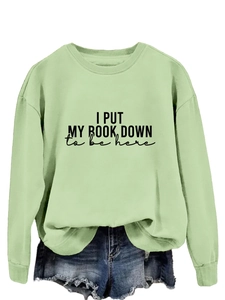 Close-up of light green sweatshirt with I PUT MY BOOK DOWN text and ribbed cuffs
