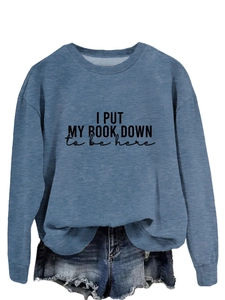 Detail of blue crewneck sweatshirt with 'I PUT MY BOOK DOWN to be here' text and denim shorts