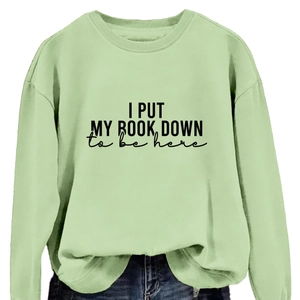 Mint green crewneck sweatshirt with 'I PUT MY BOOK DOWN' print paired with jeans