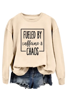 Close-up of Apricot sweatshirt with Fueled by Caffeine and Chaos print and denim shorts
