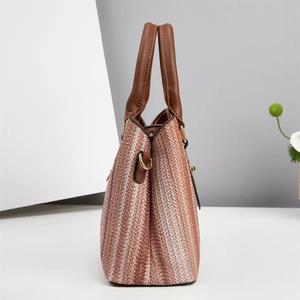 Détail du sac cabas tissé montrant le motif diagonal bicolore et l'anse en cuir