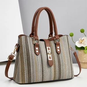 Striped woven handbag with brown leather straps and gold hardware in a modern setting